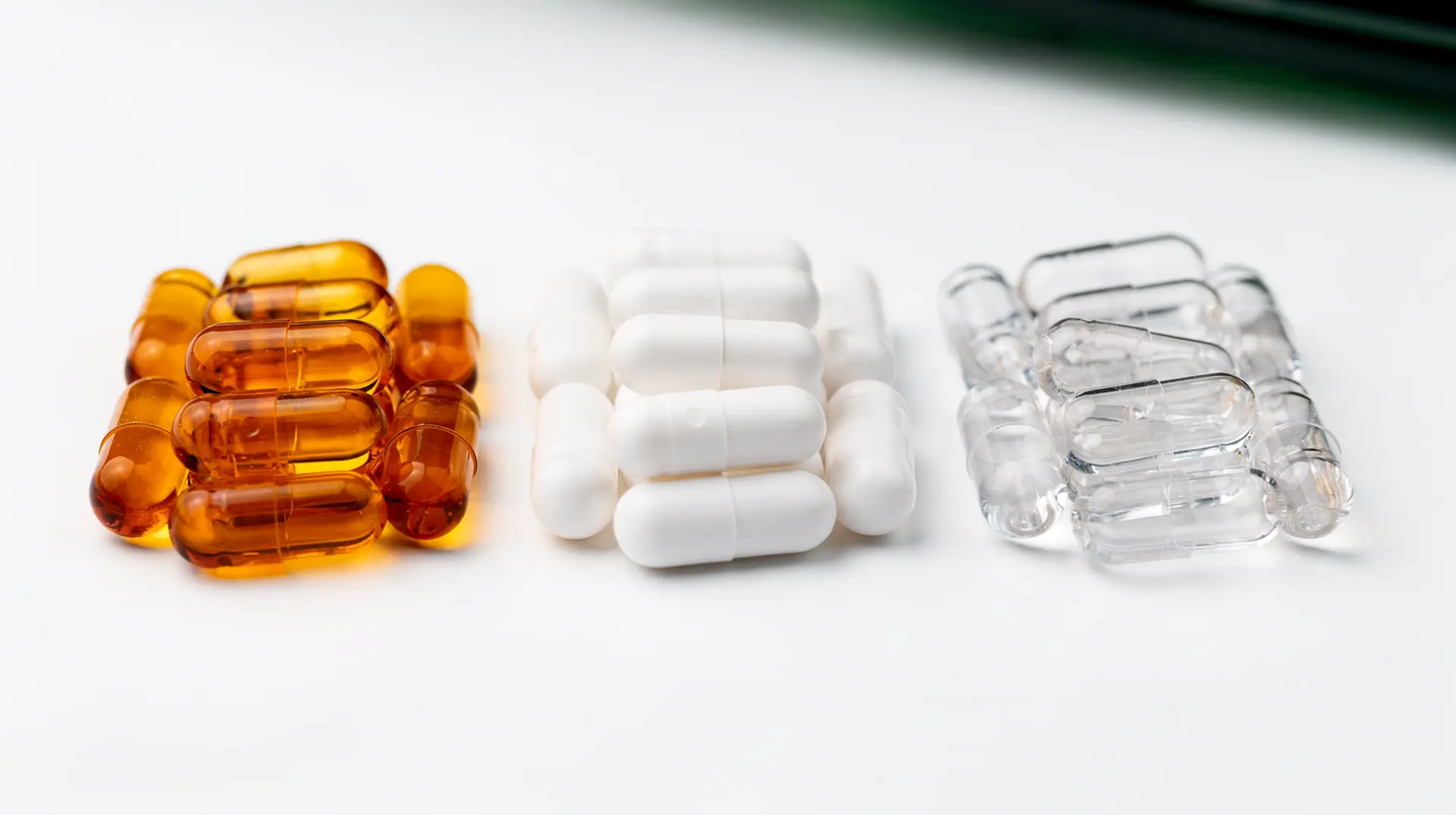 Three groups of empty two-piece capsule shells — honey gelatine, matte white HPMC and clear pullulan