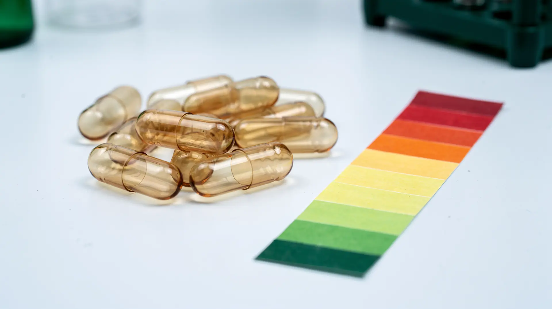Empty transparent acid-resistant hard capsule shells beside pH indicator strips